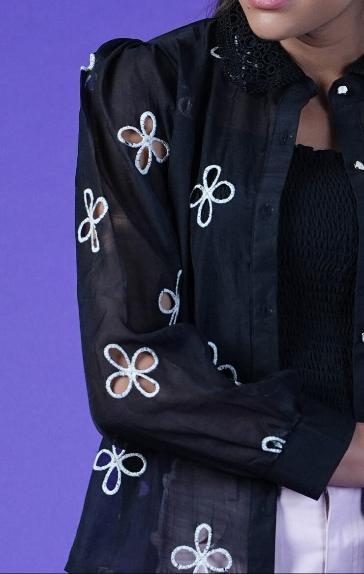 Black shirt with white floral cut work embroidery on a purple background