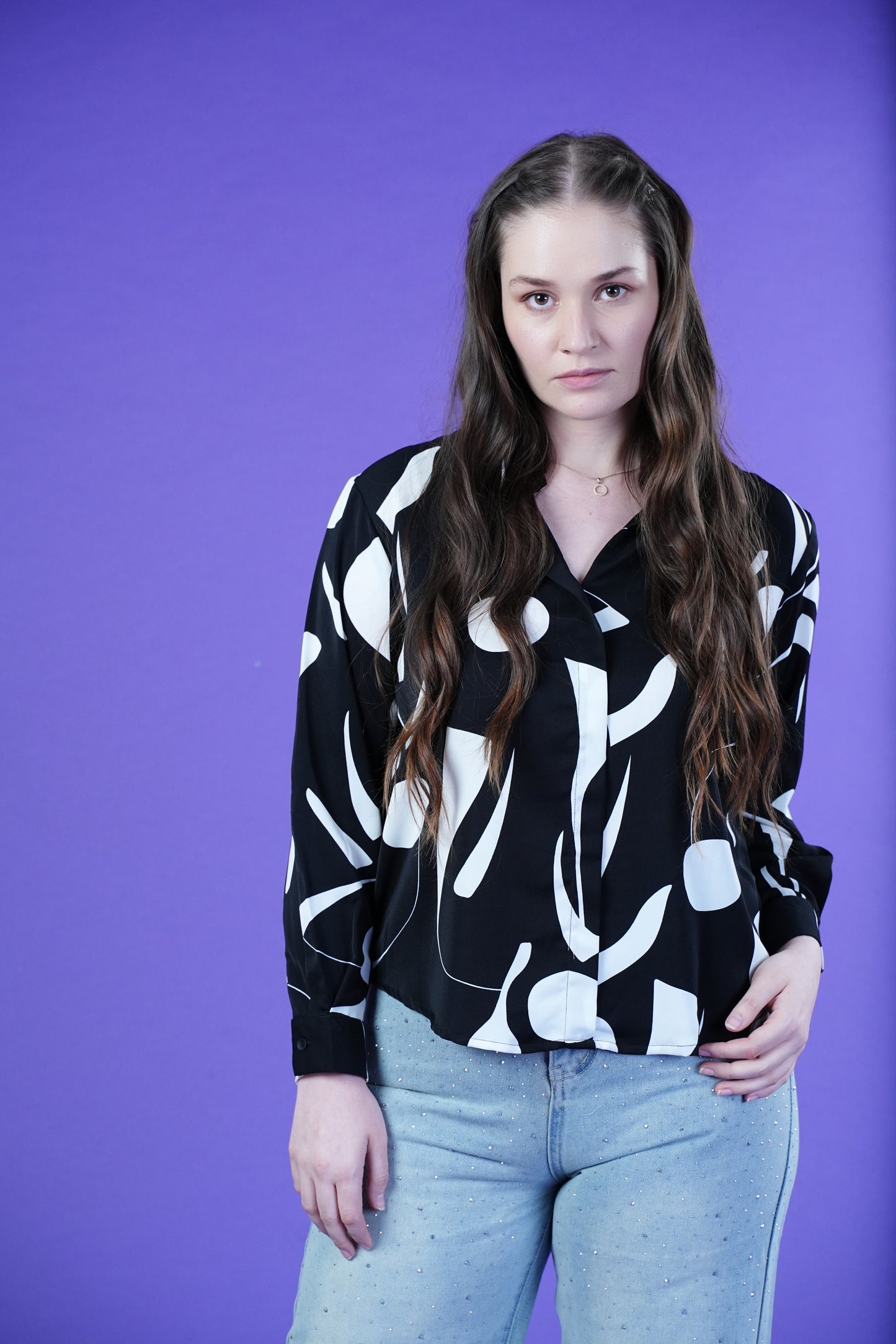 Woman wearing the OH MY MY black and white printed shirt against a purple background