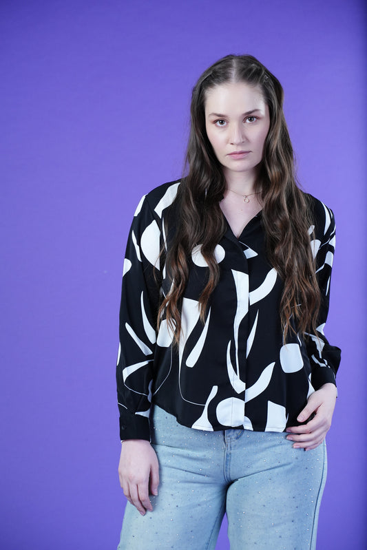Woman wearing the OH MY MY black and white printed shirt against a purple background